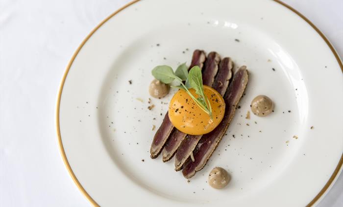Thinly sliced cured duck with wild garlic sauce and egg yolk